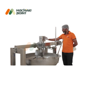 A man operating a 5-feet stainless steel halwa making machine with automated stirring, used in commercial food preparation.